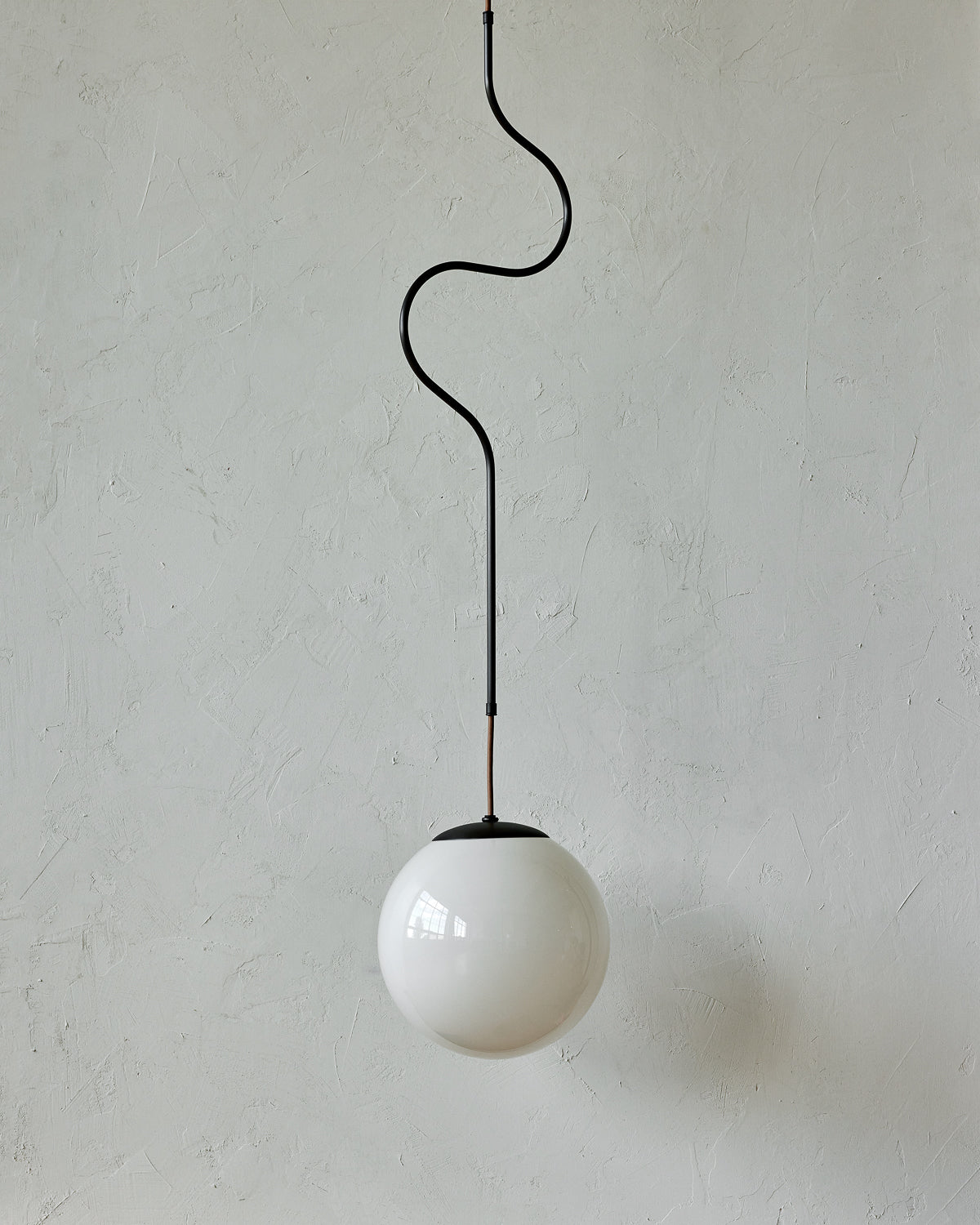 Modern black globe pendant light with dark oil rubbed brass curved body and white milk glass globe