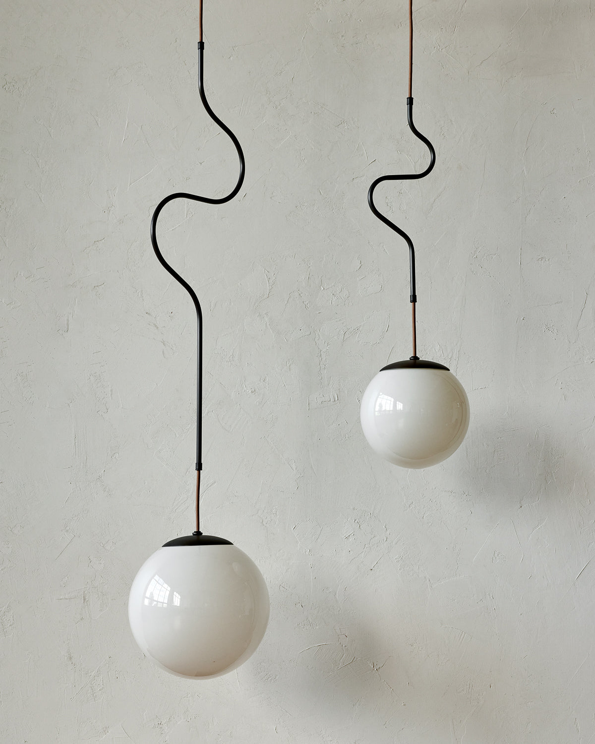 Modern black globe pendant light with dark oil rubbed brass curved body and white milk glass globe