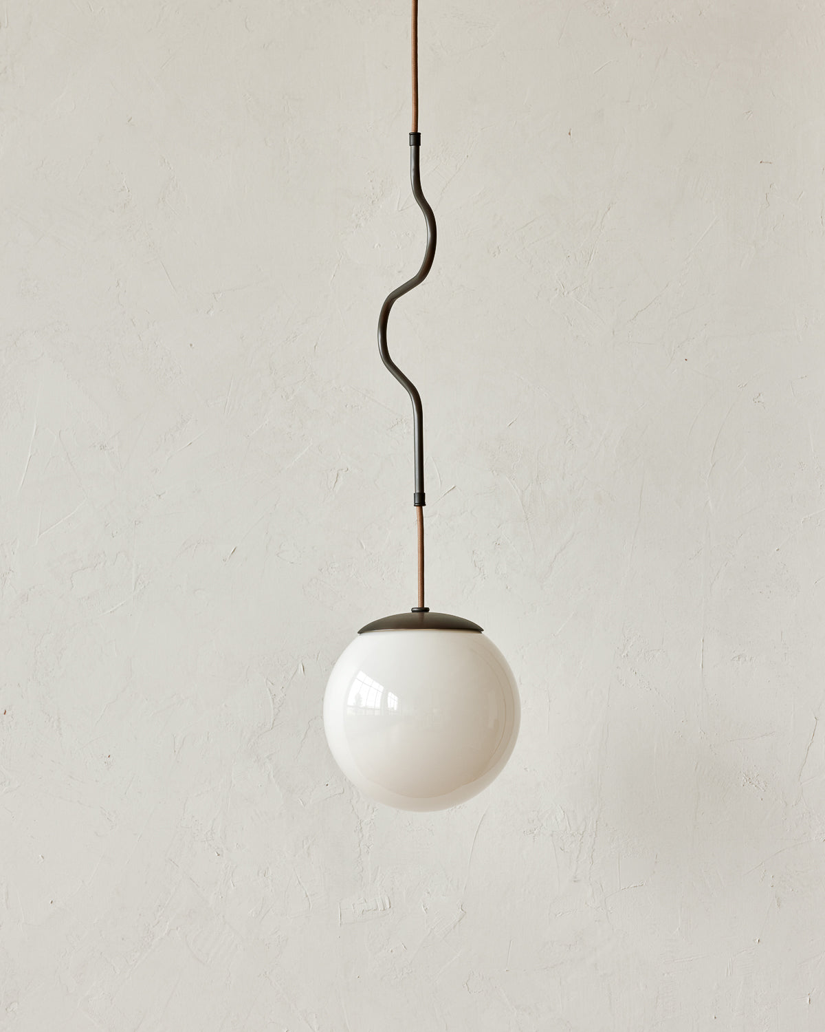 Modern black globe pendant light with dark oil rubbed brass curved body and white milk glass globe