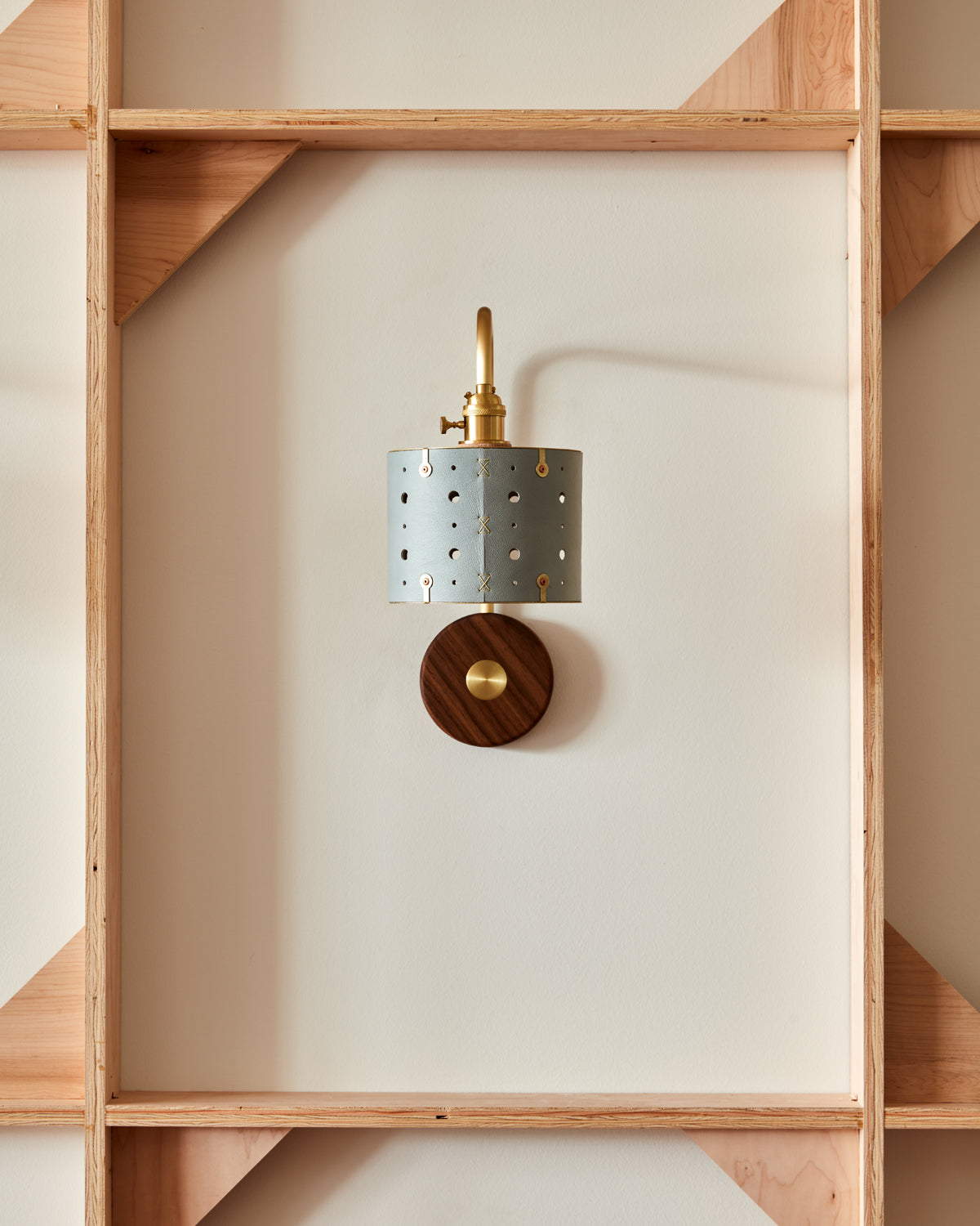 Articulating satin brass sconce with blue handstitched leather shade and walnut backplate