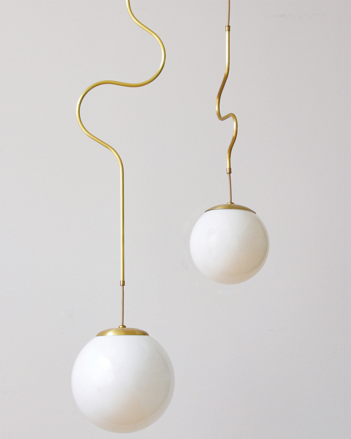 Satin brass Contour ceiling pendant lights made by Lostine in Philadelphia, Pennsylvania. Satin brass modern lighting design with white glass globe. Hardwired light fixture. Simple interior design, made in the USA.