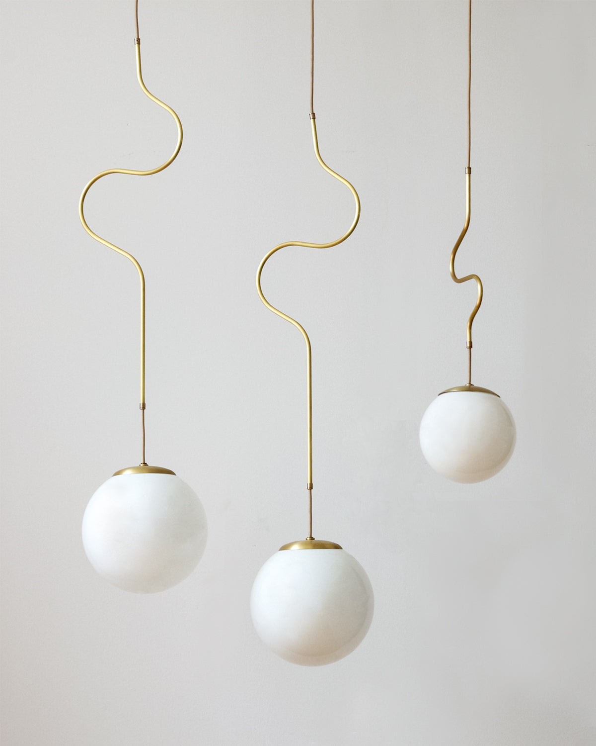 Satin brass Contour ceiling pendant lights made by Lostine in Philadelphia, Pennsylvania. Satin brass modern lighting design with white glass globe. Hardwired light fixture. Simple interior design, made in the USA.