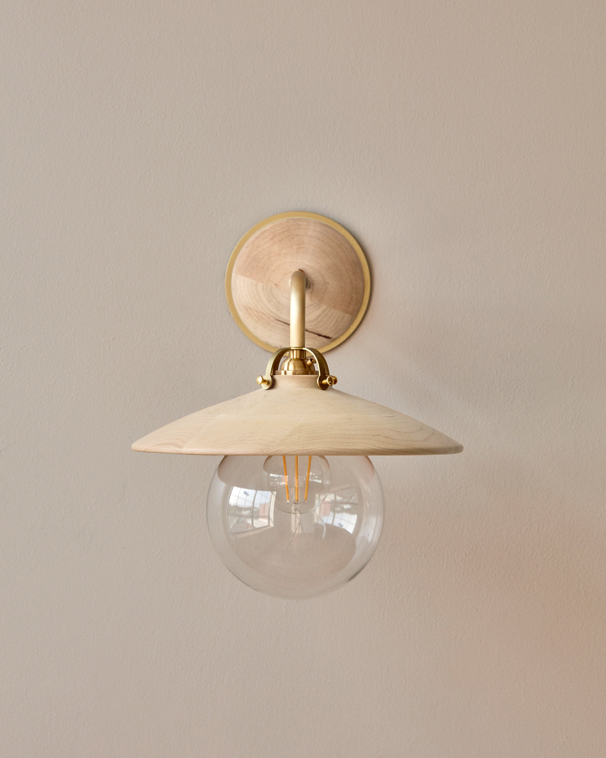 Hardwired satin brass wall sconce with decorative wooden clear maple shade and glass globe