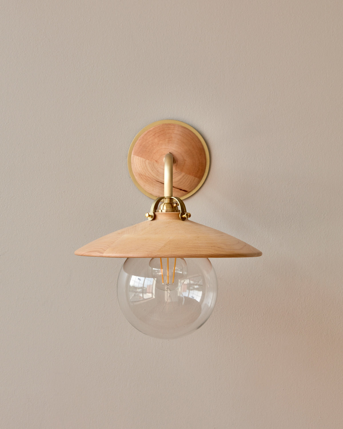 Hardwired satin brass wall sconce with decorative wooden natural maple shade and glass globe