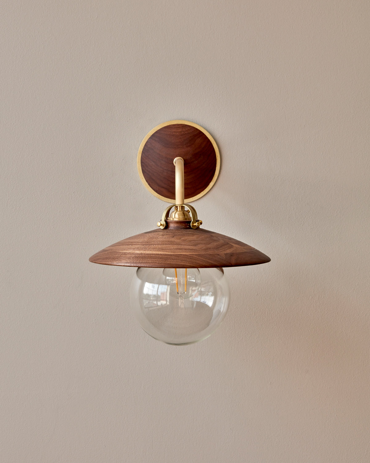 Hardwired satin brass wall sconce with decorative wooden black walnut shade and glass globe