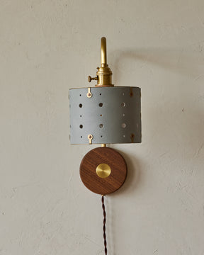 Articulating satin brass sconce with blue handstitched shade and walnut backplate