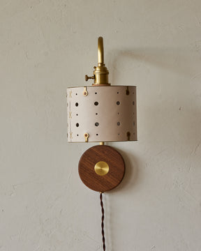 Articulating satin brass plug-in wall sconce with white handstitched shade and walnut backplate