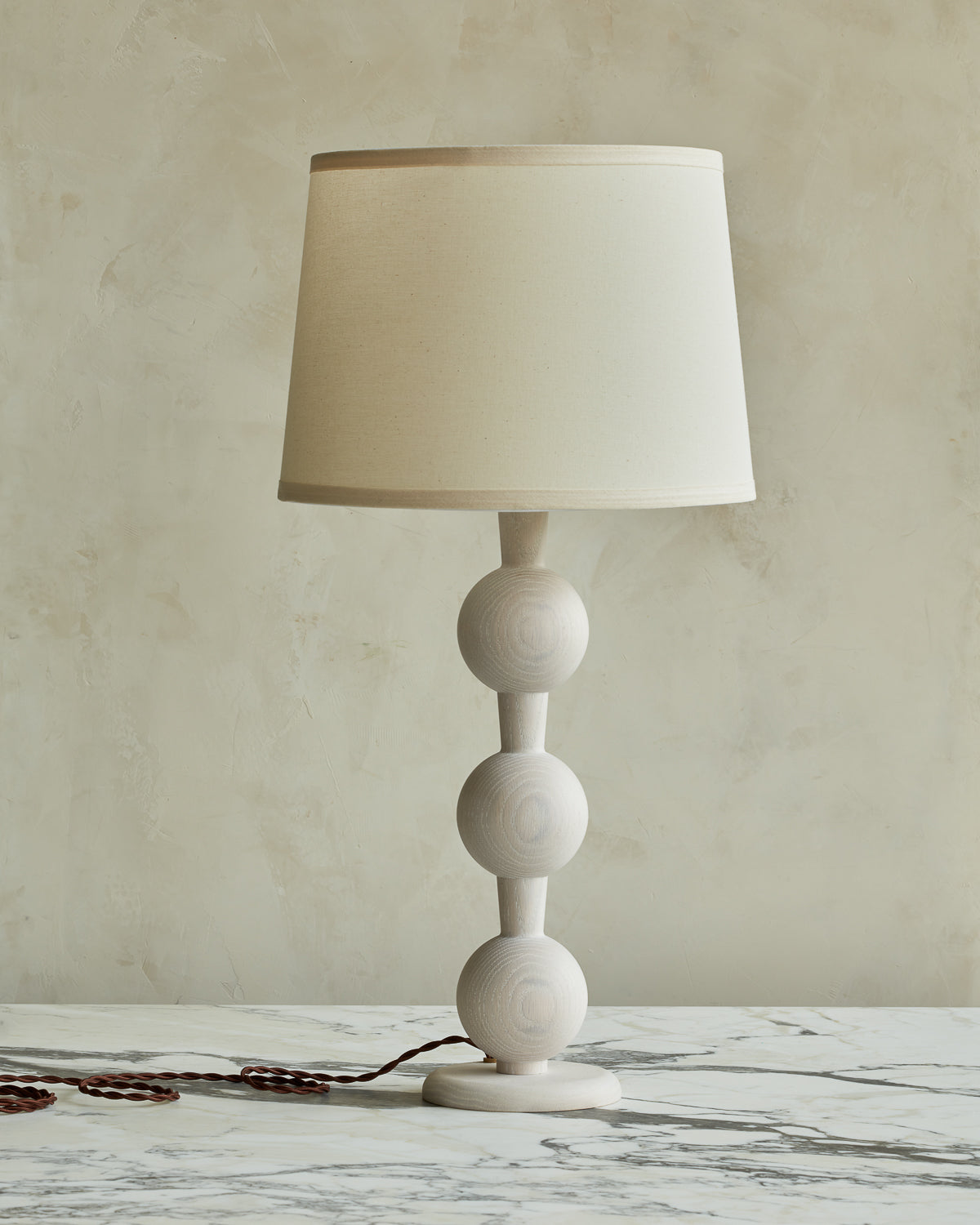 Sculptural solid wood table lamp with barbell design in white wash finish with ivory linen shade