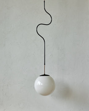 Modern black globe pendant light with dark oil rubbed brass curved body and white milk glass globe