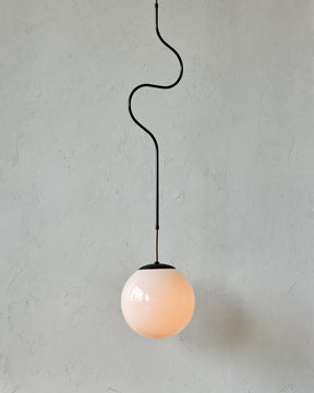 Modern black globe pendant light with dark oil rubbed brass curved body and white milk glass globe