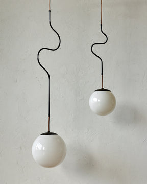 Modern black globe pendant light with dark oil rubbed brass curved body and white milk glass globe