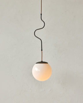Modern black globe pendant light with dark oil rubbed brass curved body and white milk glass globe