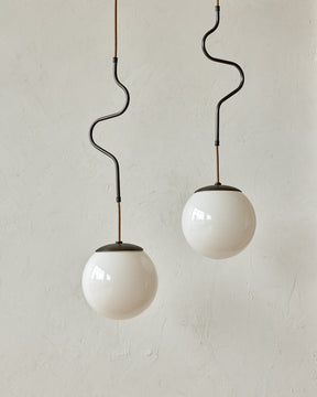 Modern black globe pendant light with dark oil rubbed brass curved body and white milk glass globe