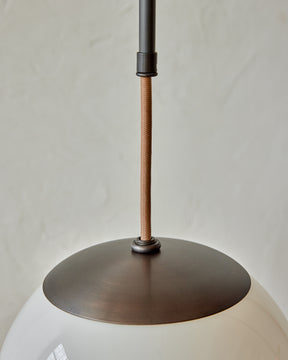 Modern black globe pendant light with dark oil rubbed brass curved body and white milk glass globe