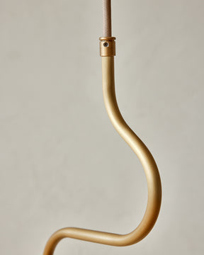 Modern brass globe pendant light with warm satin brass curved body and white milk glass globe