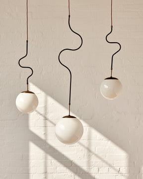 Modern black globe pendant light with dark oil rubbed brass curved body and white milk glass globe
